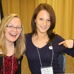 Two women point to an "I love writing" pin